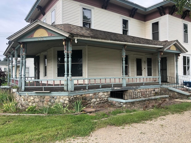 view of front facade with covered porch and a shingled roof