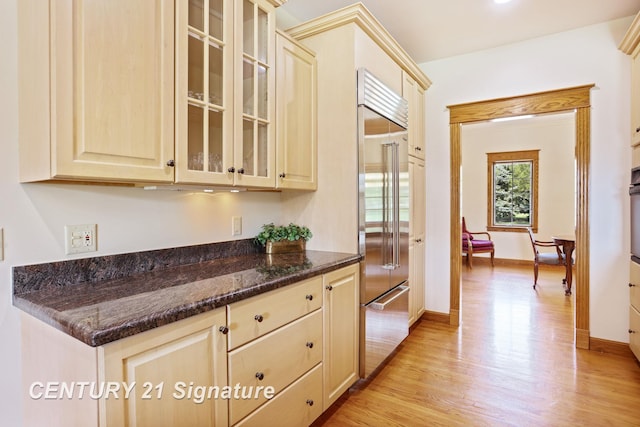 43 Sawmill Creek Trl, Saginaw, MI 48603 - kitchen with built in refrigerator, light wood-style flooring, glass insert cabinets, dark stone counters, and light brown cabinetry