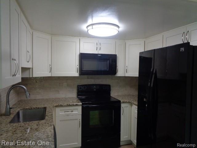 26537 Summerdale Dr, Southfield, MI 48033 - kitchen with black appliances, white cabinetry, and tasteful backsplash