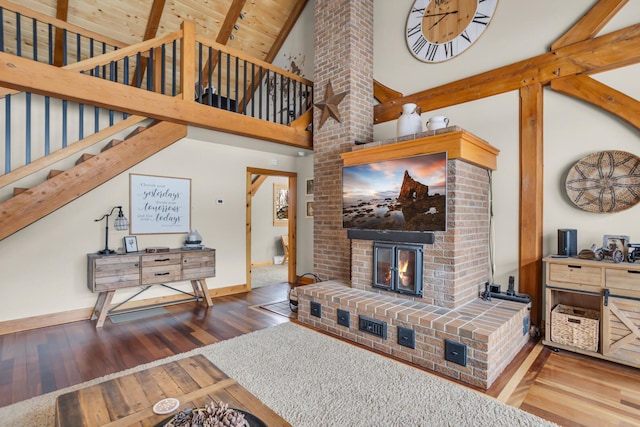 12500 Round Lake Rd, Horton, MI 49246 - living room with wood finished floors, beam ceiling, decorative columns, a fireplace, and stairway