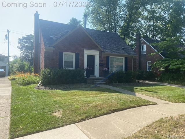 1417 N Maple Ave, Royal Oak, MI 48067 - view of front facade featuring brick siding, a chimney, a front lawn, and a shingled roof
