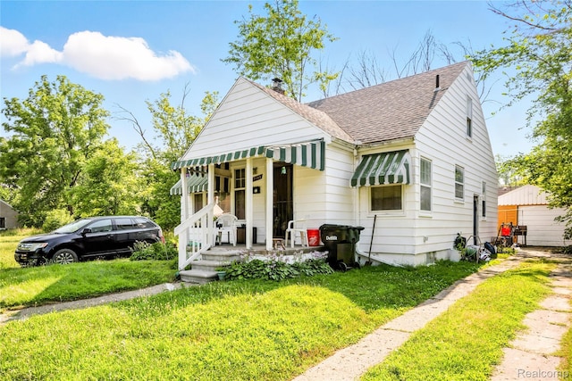 18995 Fielding St, Detroit, MI 48219 - bungalow-style house with roof with shingles, a front yard, a chimney, and an outbuilding
