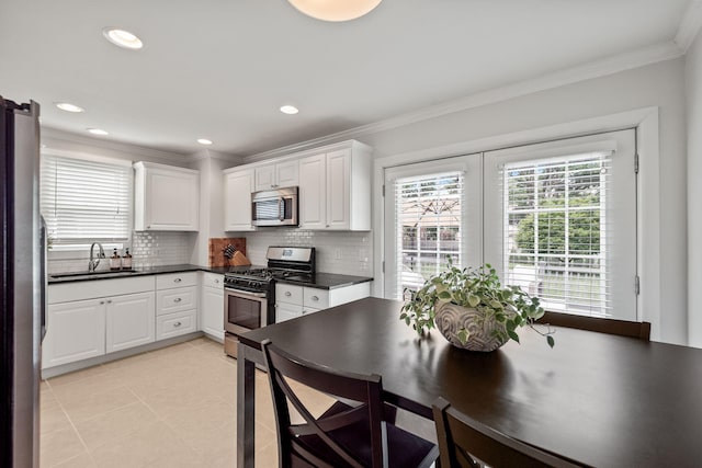 2213 N Wilson Ave, Royal Oak, MI 48073 - kitchen with appliances with stainless steel finishes, dark countertops, backsplash, white cabinetry, and ornamental molding