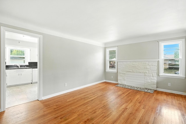 2707 Byron Center Ave SW, Wyoming, MI 49519 - unfurnished living room with healthy amount of natural light, light wood-style floors, and a stone fireplace