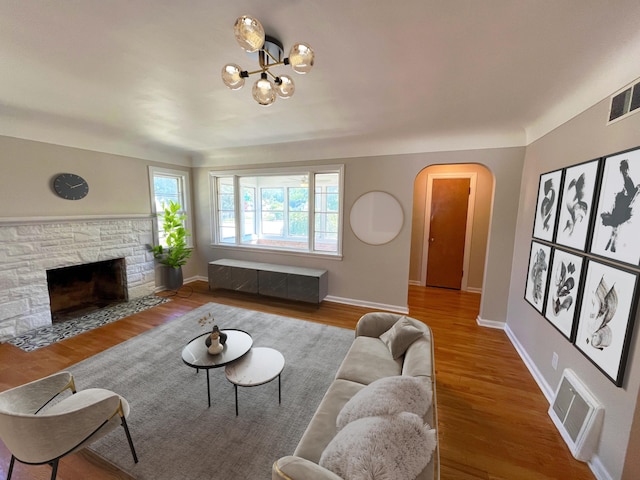 2707 Byron Center Ave SW, Wyoming, MI 49519 - living area with arched walkways, wood finished floors, a stone fireplace, and a chandelier