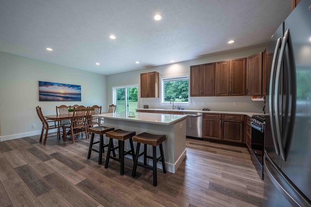 7898 W Juniper Beach Rd, Mears, MI 49436 - kitchen with appliances with stainless steel finishes, light countertops, a center island, a breakfast bar area, and recessed lighting