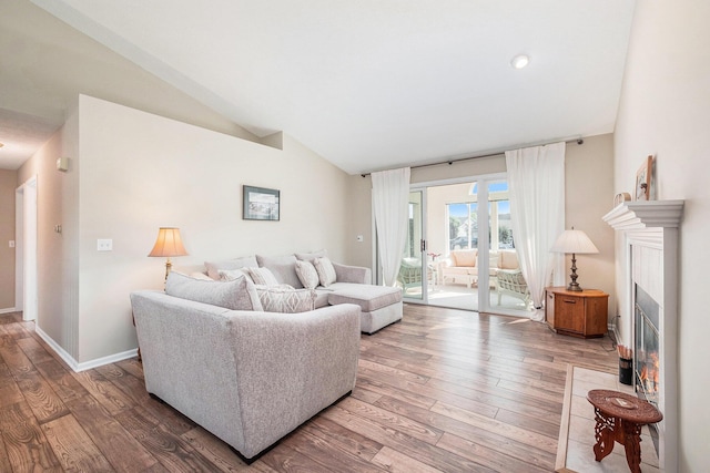 5766 Wineberry Ln SW, Wyoming, MI 49418 - living area featuring a fireplace with flush hearth, wood-type flooring, and vaulted ceiling
