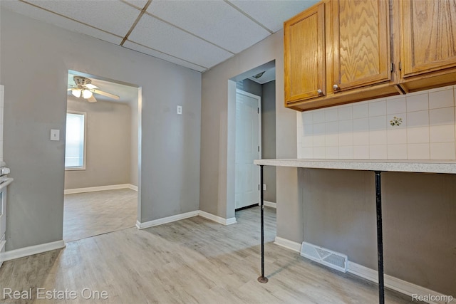 1425 Lincoln Ave, Flint, MI 48507 - kitchen featuring light wood-style floors, light countertops, ceiling fan, a drop ceiling, and brown cabinets