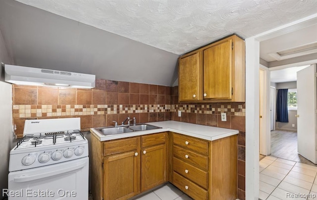 1425 Lincoln Ave, Flint, MI 48507 - kitchen featuring gas range gas stove, under cabinet range hood, light tile patterned floors, light countertops, and lofted ceiling
