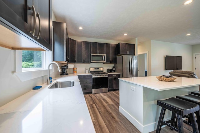 7920 W Juniper Beach Rd, Mears, MI 49436 - kitchen featuring appliances with stainless steel finishes, a kitchen breakfast bar, dark wood-style floors, recessed lighting, and light countertops