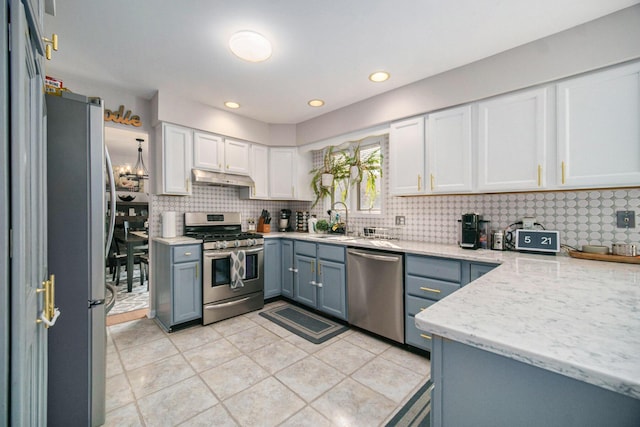 1101 Heritage Dr, Saline, MI 48176 - kitchen with appliances with stainless steel finishes, white cabinets, tasteful backsplash, light stone countertops, and under cabinet range hood