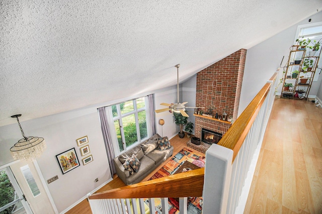1101 Heritage Dr, Saline, MI 48176 - living area with a textured ceiling, wood finished floors, lofted ceiling, a fireplace, and a ceiling fan