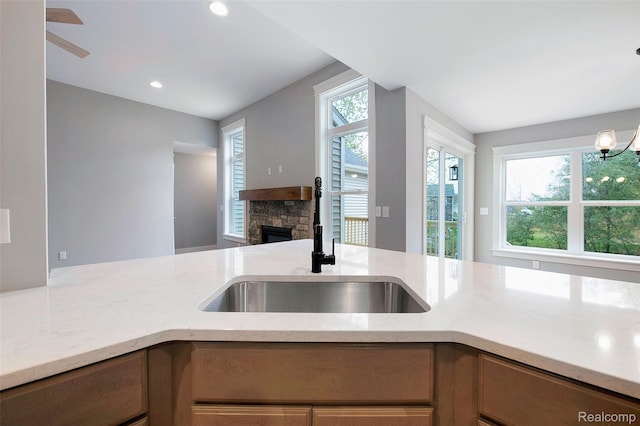 13339 Whispering Pines Ct, Linden, MI 48451 - kitchen with a stone fireplace, light stone countertops, and recessed lighting