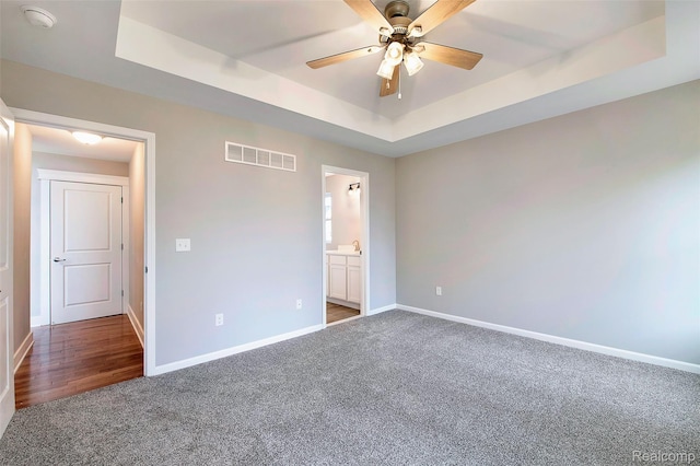 13339 Whispering Pines Ct, Linden, MI 48451 - unfurnished bedroom featuring a raised ceiling, carpet floors, connected bathroom, and ceiling fan