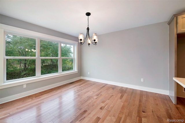 13339 Whispering Pines Ct, Linden, MI 48451 - spare room featuring a chandelier, healthy amount of natural light, and light wood-style flooring