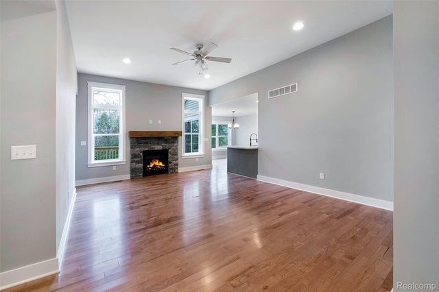 13339 Whispering Pines Ct, Linden, MI 48451 - unfurnished living room featuring ceiling fan, wood finished floors, a fireplace, recessed lighting, and a chandelier