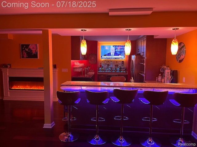 24352 Cavendish Ave W, Novi, MI 48375 - indoor wet bar featuring stainless steel double oven, hanging light fixtures, and a glass covered fireplace