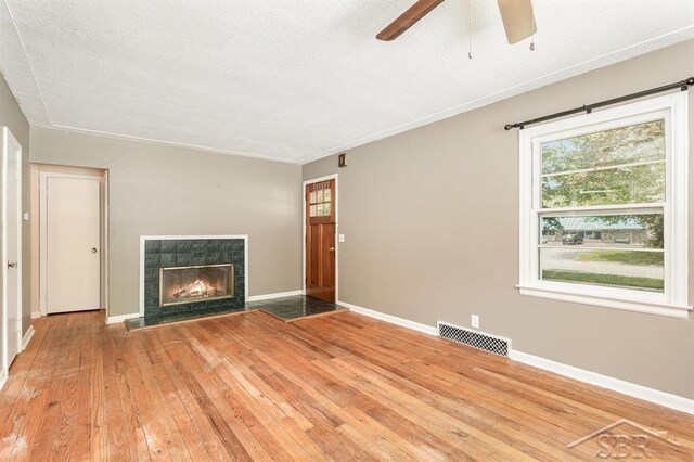 114 E Sugnet Rd, Midland, MI 48642 - unfurnished living room with hardwood / wood-style floors, a ceiling fan, plenty of natural light, and a tiled fireplace