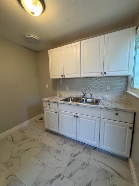 3033 Williams St, Inkster, MI 48141 - kitchen with white cabinets, light marble finish floors, and backsplash