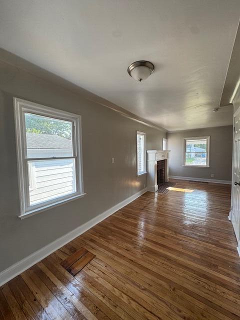 3033 Williams St, Inkster, MI 48141 - unfurnished living room with a brick fireplace and hardwood / wood-style flooring