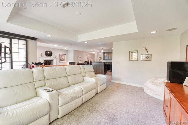 10827 Sparkling Waters Ct, South Lyon, MI 48178 - living room featuring light colored carpet, a raised ceiling, recessed lighting, and a glass covered fireplace