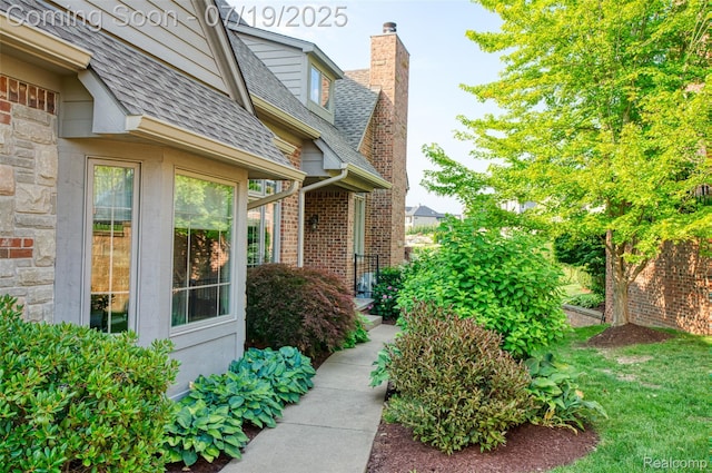 10827 Sparkling Waters Ct, South Lyon, MI 48178 - entrance to property featuring roof with shingles, a chimney, and stone siding