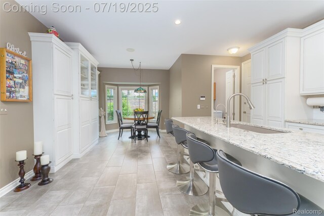 10827 Sparkling Waters Ct, South Lyon, MI 48178 - kitchen with white cabinetry, light stone counters, a breakfast bar area, and recessed lighting