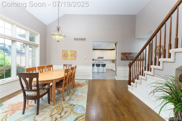 10827 Sparkling Waters Ct, South Lyon, MI 48178 - dining area with wood finished floors, plenty of natural light, high vaulted ceiling, stairs, and wainscoting