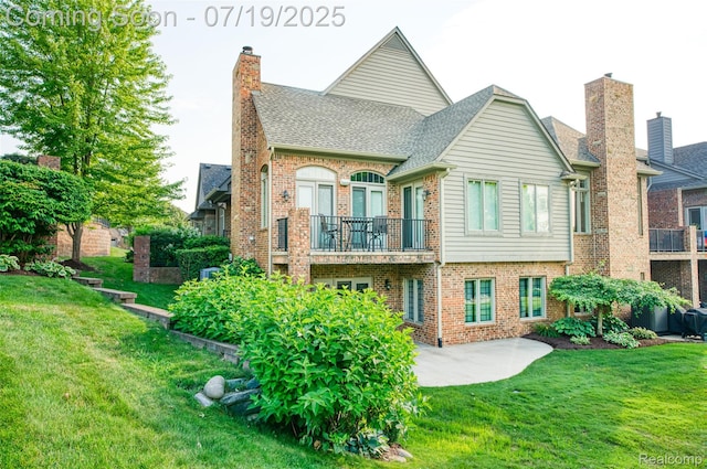 10827 Sparkling Waters Ct, South Lyon, MI 48178 - back of house featuring a balcony, brick siding, a lawn, roof with shingles, and a chimney