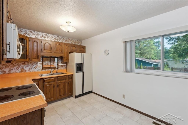 3118 Spruce St, Midland, MI 48640 - kitchen featuring white fridge with ice dispenser, light countertops, glass insert cabinets, a textured ceiling, and brown cabinets