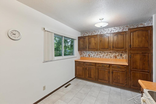 3118 Spruce St, Midland, MI 48640 - kitchen featuring light countertops, range, a textured ceiling, backsplash, and brown cabinets