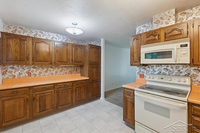 3118 Spruce St, Midland, MI 48640 - kitchen featuring white appliances, light countertops, a textured ceiling, brown cabinets, and wallpapered walls