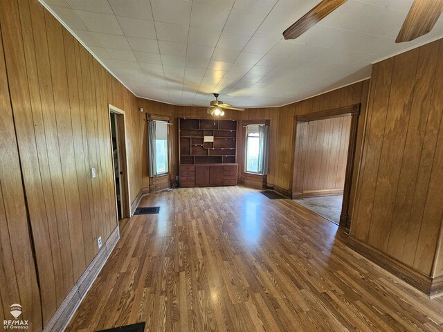 725 River St, Owosso, MI 48867 - unfurnished living room with wood walls, a ceiling fan, and wood finished floors