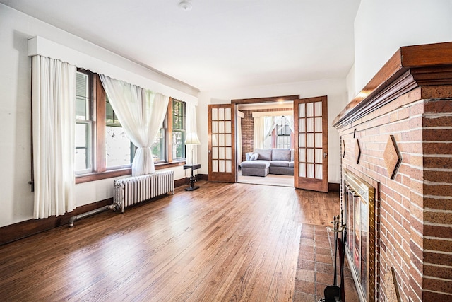 2551 Elmwood Ave, Ann Arbor, MI 48104 - living area featuring wood finished floors, radiator, french doors, and a fireplace