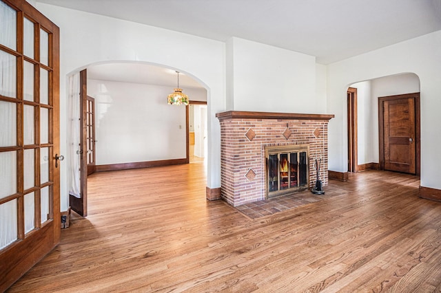2551 Elmwood Ave, Ann Arbor, MI 48104 - unfurnished living room with wood finished floors, a fireplace, and arched walkways