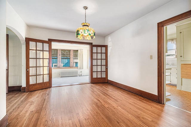2551 Elmwood Ave, Ann Arbor, MI 48104 - unfurnished room featuring wood finished floors, arched walkways, radiator, and french doors