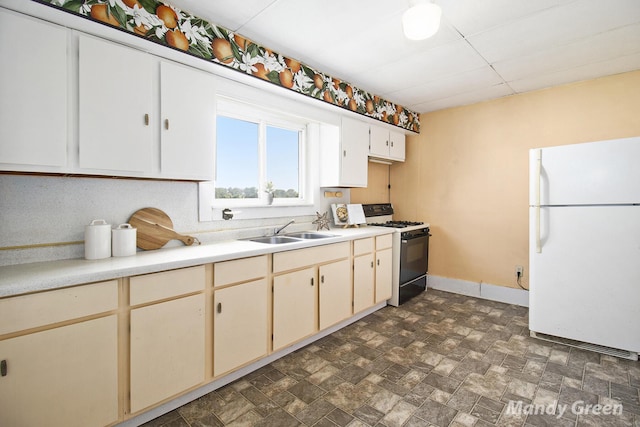 4651 E Pierce Rd, Ithaca, MI 48847 - kitchen with freestanding refrigerator, gas stove, light countertops, stone finish floors, and cream cabinets