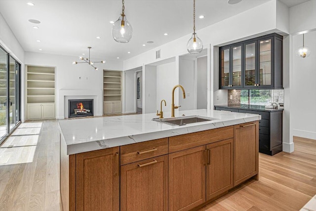 7462 Youngren Rd, Three Oaks, MI 49128 - kitchen with light wood finished floors, built in shelves, light stone counters, brown cabinetry, and recessed lighting