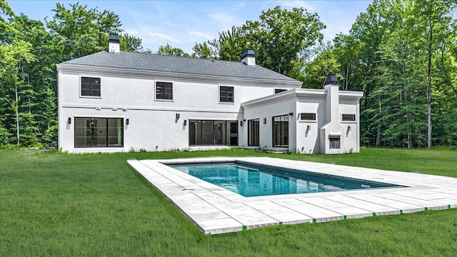 7462 Youngren Rd, Three Oaks, MI 49128 - back of house featuring a chimney, an outdoor pool, a lawn, and stucco siding