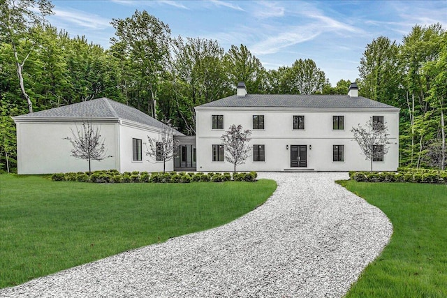 7462 Youngren Rd, Three Oaks, MI 49128 - view of front of home featuring a chimney, a front lawn, gravel driveway, and stucco siding