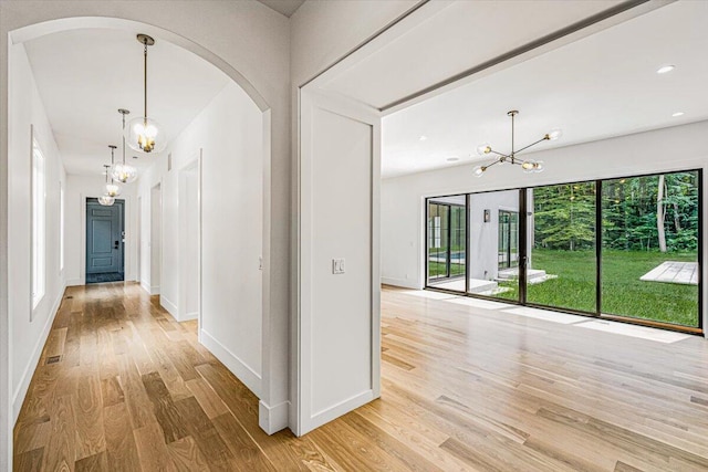 7462 Youngren Rd, Three Oaks, MI 49128 - corridor with a chandelier, light wood-style flooring, arched walkways, and recessed lighting