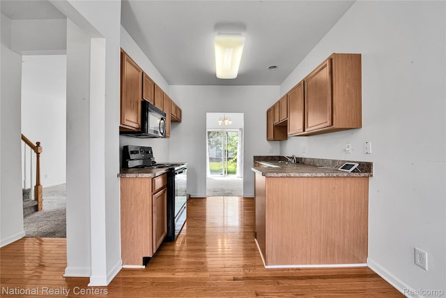 1236 University Dr, Pontiac, MI 48342 - kitchen with black electric range oven, light wood-type flooring, dark countertops, and brown cabinetry