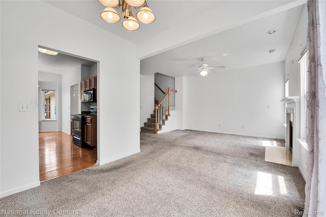1236 University Dr, Pontiac, MI 48342 - unfurnished living room featuring carpet flooring, stairs, a fireplace with flush hearth, a chandelier, and a ceiling fan