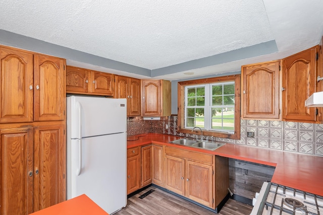 5010 N Pendell Rd, Alma, MI 48801 - kitchen with freestanding refrigerator, a textured ceiling, brown cabinets, decorative backsplash, and light wood finished floors