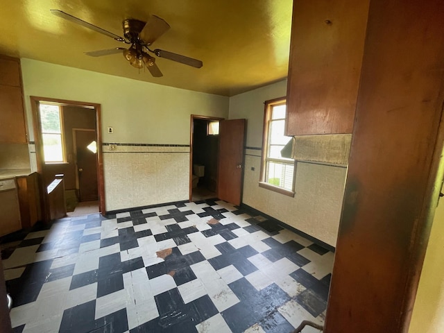 262 5th St, Manistee, MI 49660 - kitchen featuring tile patterned floors, ceiling fan, white dishwasher, wainscoting, and light countertops