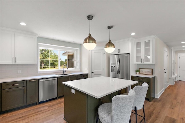 6766 Baldwin St, Hudsonville, MI 49426 - kitchen with stainless steel appliances, white cabinetry, glass insert cabinets, a center island, and light wood-style floors