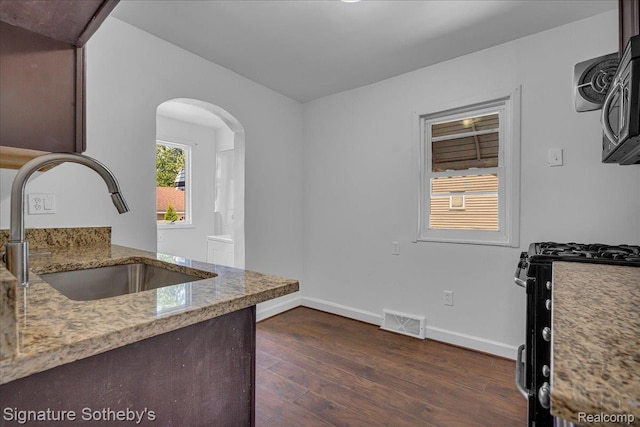 1221 E 13 Mile Rd, Royal Oak, MI 48073 - kitchen with arched walkways, light stone countertops, dark wood finished floors, range with gas stovetop, and stainless steel microwave