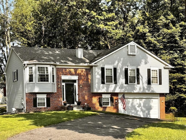 1501 Kings Crown Ct, Wixom, MI 48393 - split foyer home with brick siding, asphalt driveway, an attached garage, a chimney, and a front yard