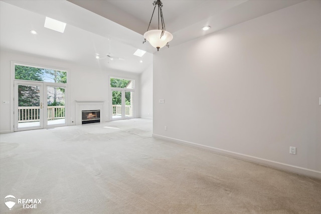 8078 Hawkcrest Dr, Grand Blanc, MI 48439 - unfurnished living room with a skylight, light carpet, a glass covered fireplace, and recessed lighting