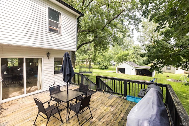 1193 Seneca St, Adrian, MI 49221 - wooden deck with outdoor dining area, a yard, an outbuilding, and a trampoline